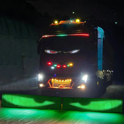 A truck adorned with vibrant lighting from the Smart LED Pixel Panel – Light Up Your Space with Custom Animations, featuring glowing eyes and animated lines, drives at night, creating a dramatic and eye-catching effect on the dark road.